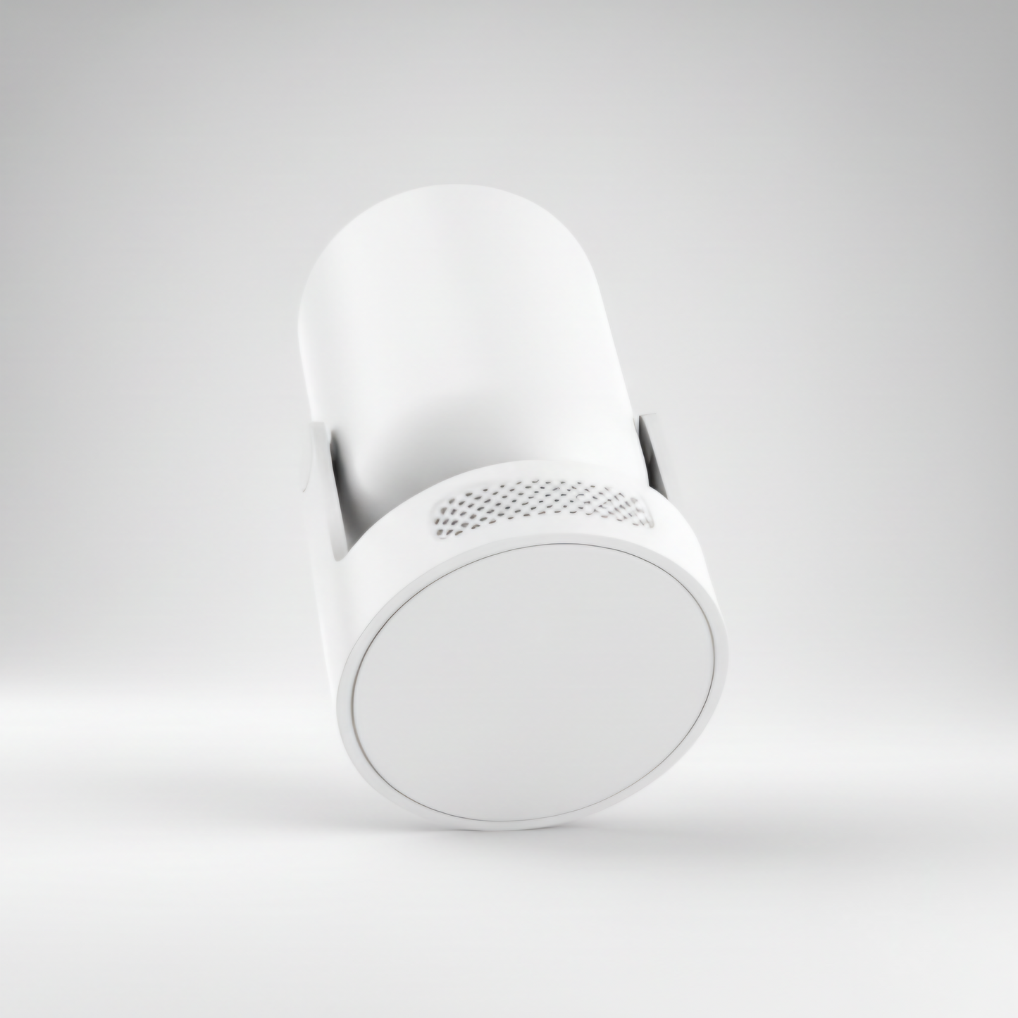 A minimal, angled studio shot of a white cylindrical smart device, likely a portable projector or home security camera, against a neutral white background. The bottom end of the cylinder is visible, showing a smooth white cap and a subtly textured perforated grille near the base, suggesting speaker or ventilation openings. The device is mounted on a small, unobtrusive white stand. Keywords include minimalist smart home device, wireless mini projector, sleek electronics design, white camera casing, and mode