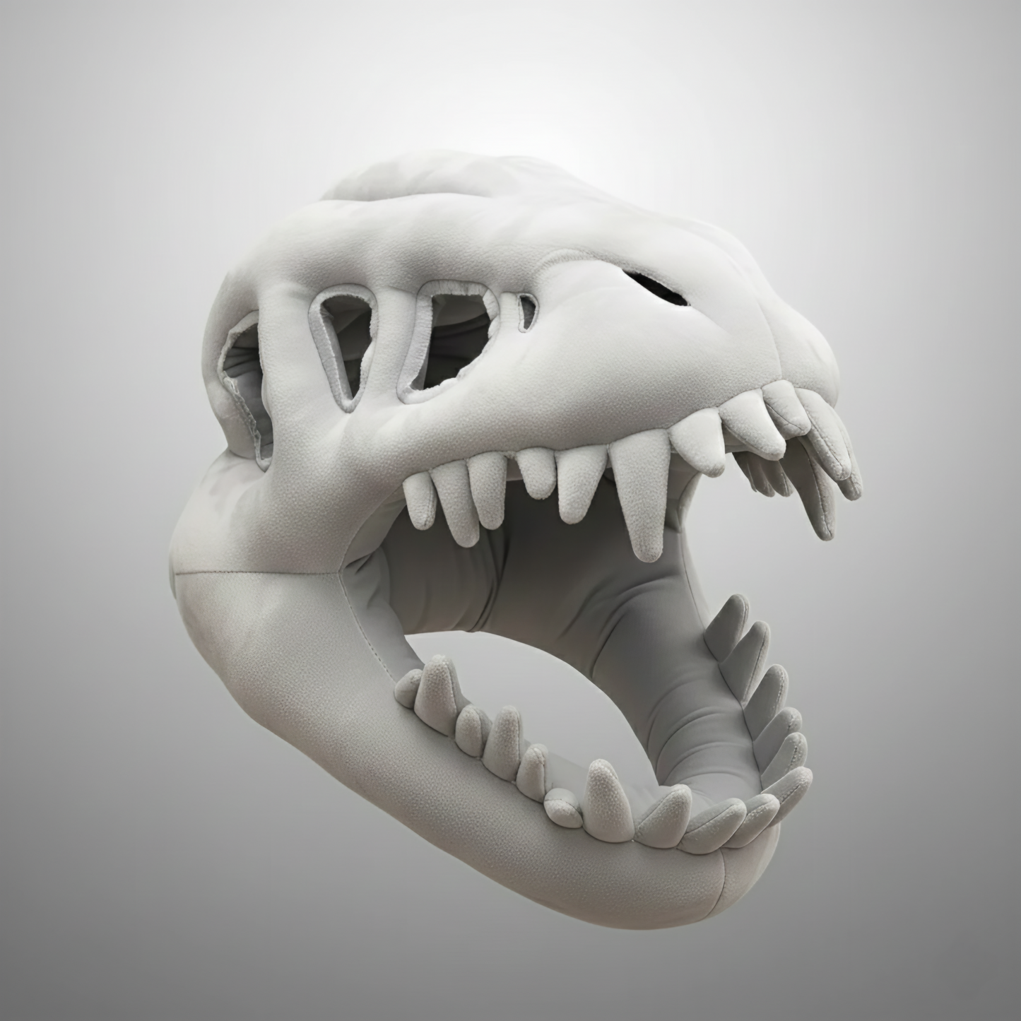 A close-up studio shot of a plush grey dinosaur skull mask or headpiece, isolated against a white-to-grey gradient background. The costume accessory is intricately designed to look like a T-Rex skeleton or paleontological fossil, featuring large eye sockets, nasal openings, and a wide-open mouth displaying soft, pointed teeth. This image is valuable for dinosaur costume accessories, Halloween mask ideas, T-Rex apparel, skeleton props, and plush novelty items.