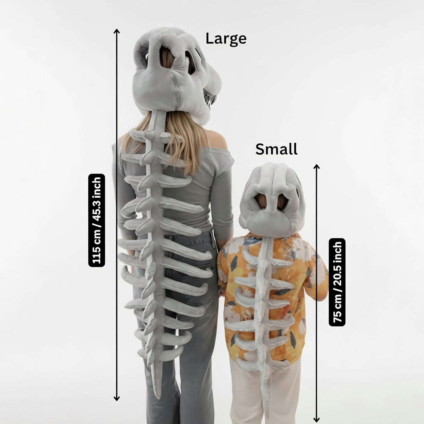 An image comparing the sizes of plush grey dinosaur skeleton costumes labeled "Large" and "Small," shown from the back against a white studio background. The Large costume is worn by a woman (in jeans and a grey shirt) and measures 115 cm / 45.3 inches from the top of the skull to the tip of the tail. The Small costume is worn by a child (in a yellow floral shirt) and measures 75 cm / 20.5 inches in length. Both dinosaur costumes feature a detailed skull hood and a long, ribbed spinal column. This image is 